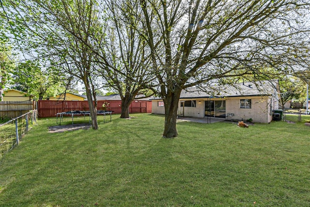 view of yard featuring a patio, a fenced backyard, and a trampoline
