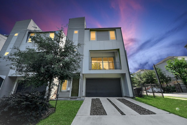 contemporary home featuring a garage, a front lawn, a balcony, and concrete driveway