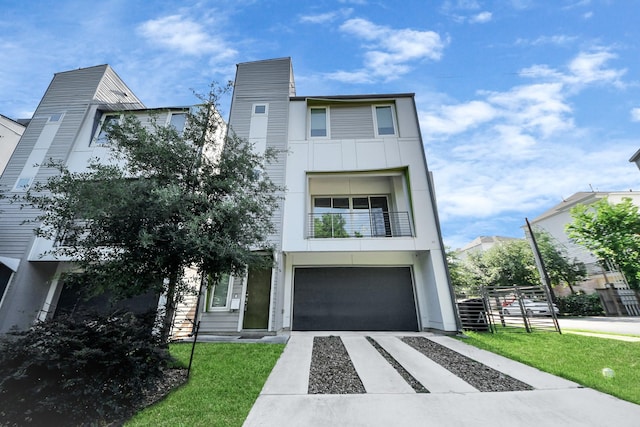 contemporary house featuring concrete driveway, an attached garage, a balcony, and a front yard