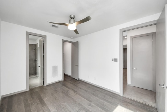 unfurnished bedroom featuring ensuite bath, wood finished floors, and visible vents