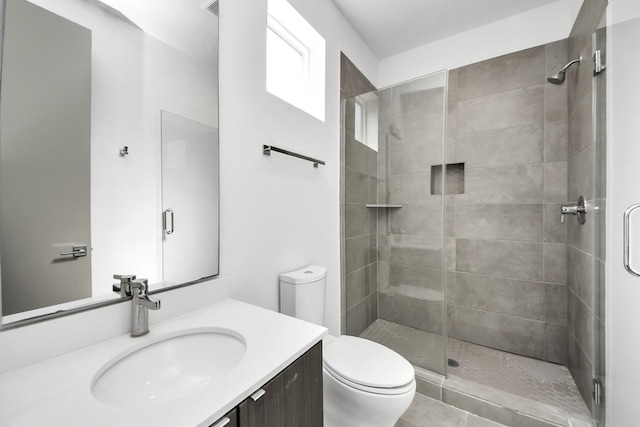bathroom featuring vanity, a shower stall, and toilet