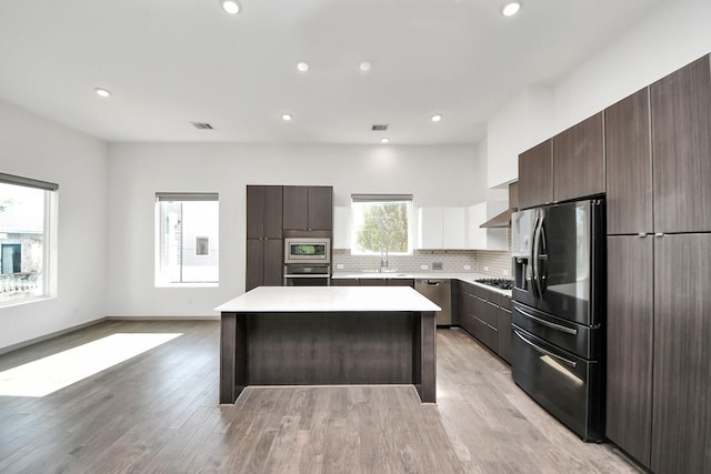 kitchen with dark brown cabinetry, a sink, stainless steel appliances, a kitchen island, and modern cabinets
