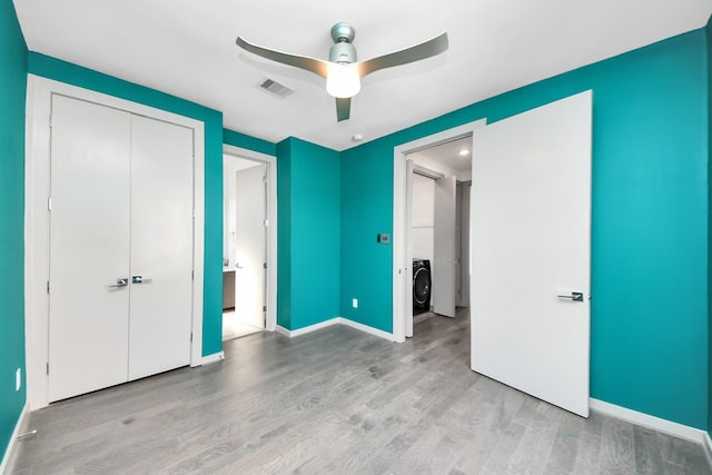 unfurnished bedroom with visible vents, washer / dryer, wood finished floors, and a closet