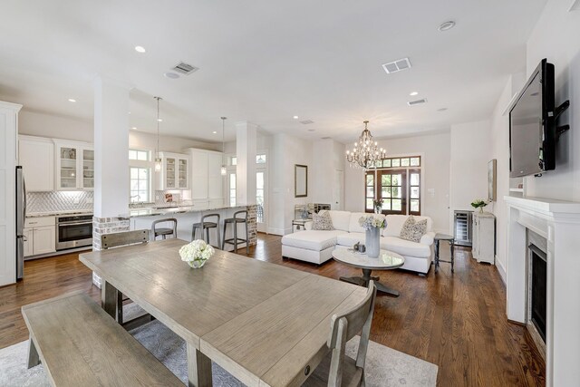 dining space with dark wood-style flooring, visible vents, a fireplace, an inviting chandelier, and recessed lighting