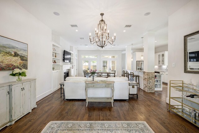 living area featuring an inviting chandelier, a fireplace, dark wood-type flooring, and visible vents