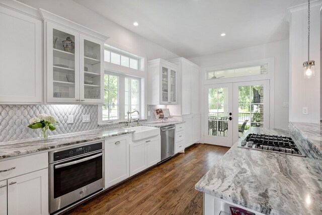 kitchen with white cabinets, appliances with stainless steel finishes, light stone counters, a sink, and french doors