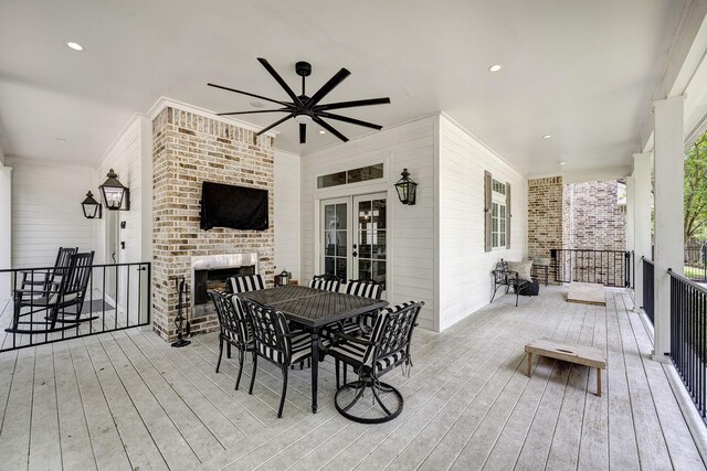 wooden deck featuring a ceiling fan, french doors, outdoor dining space, and an outdoor brick fireplace