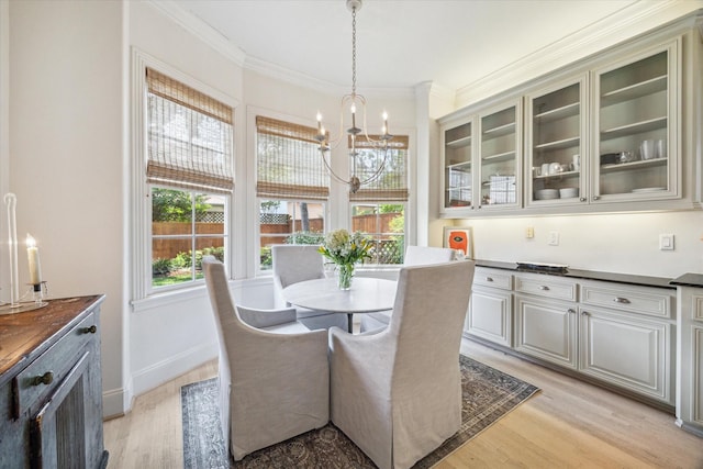 dining space with baseboards, a chandelier, ornamental molding, and light wood-style flooring