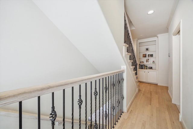 hallway with baseboards, recessed lighting, light wood finished floors, and built in features