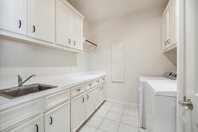 clothes washing area with baseboards, washer and clothes dryer, a sink, cabinet space, and light tile patterned floors
