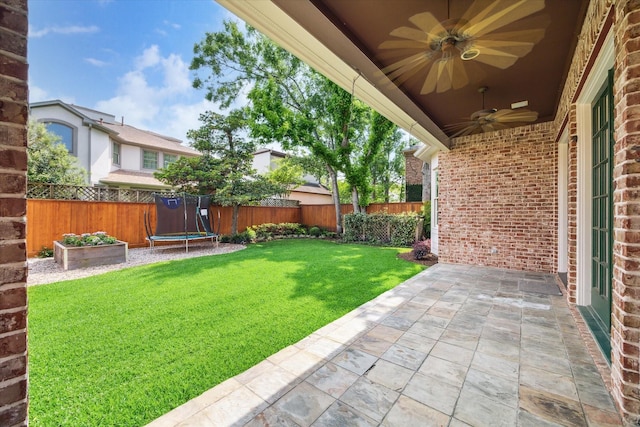 view of yard featuring a patio, a ceiling fan, a fenced backyard, and a trampoline