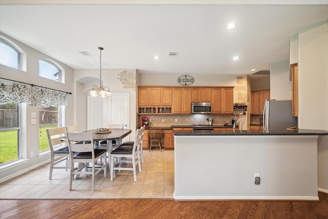 kitchen featuring dark countertops, a sink, a chandelier, stainless steel appliances, and decorative backsplash