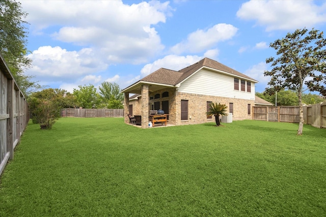 rear view of house with a fenced backyard, a patio, and a yard