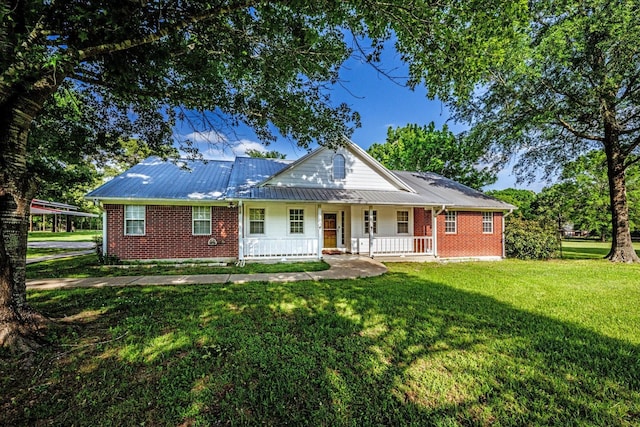 view of front of home with covered porch, metal roof, a front lawn, and brick siding