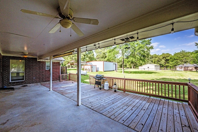 wooden terrace featuring a yard, ceiling fan, fence, and an outdoor structure