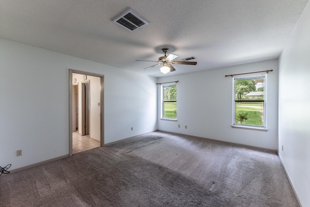carpeted spare room featuring visible vents, a ceiling fan, a textured ceiling, and baseboards