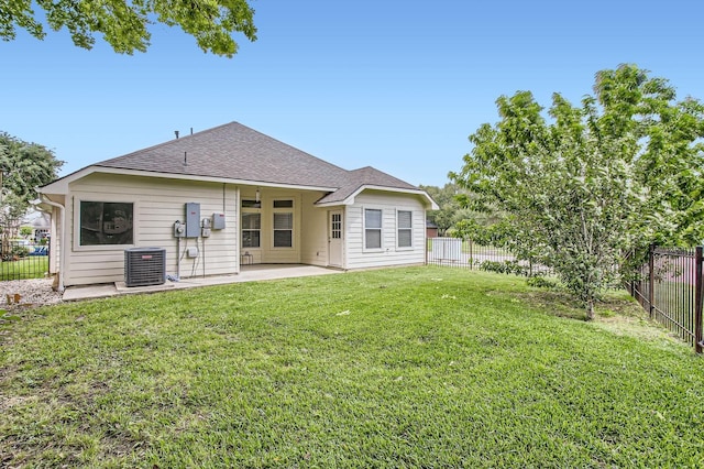 back of house with a shingled roof, a fenced backyard, cooling unit, a lawn, and a patio