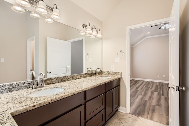 bathroom with a sink, baseboards, double vanity, and lofted ceiling