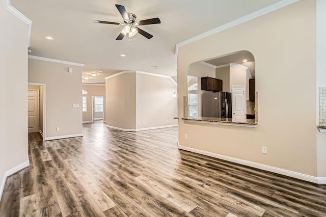 unfurnished living room featuring baseboards, a ceiling fan, wood finished floors, and ornamental molding