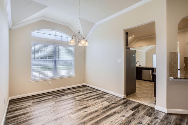 unfurnished dining area with wood finished floors, lofted ceiling, a healthy amount of sunlight, and an inviting chandelier