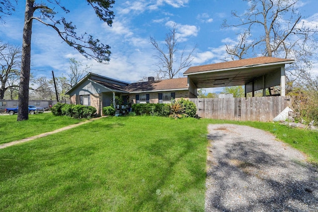 ranch-style home featuring fence, a front yard, and a carport