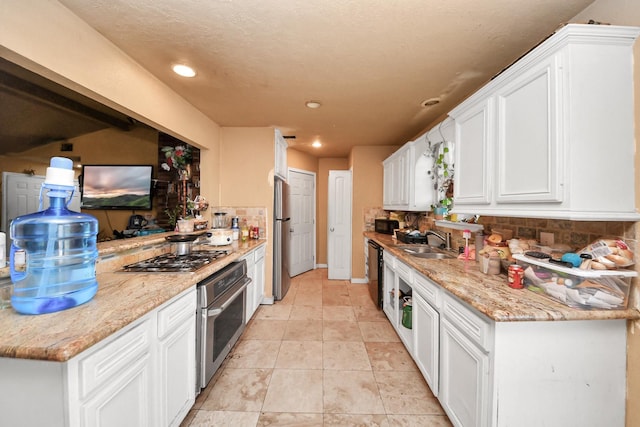 kitchen featuring a sink, appliances with stainless steel finishes, white cabinets, and backsplash