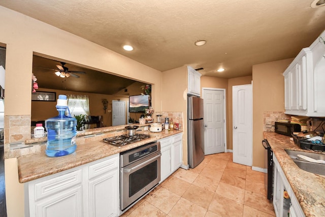 kitchen featuring ceiling fan, backsplash, stainless steel appliances, and white cabinetry