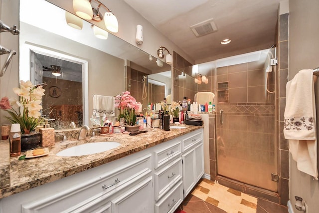 bathroom featuring double vanity, visible vents, a stall shower, a sink, and tile patterned floors