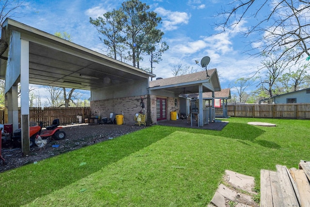 view of yard with a fenced backyard and a carport