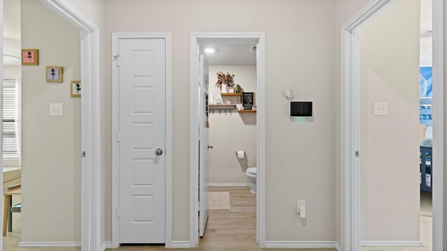 corridor with baseboards and wood finished floors