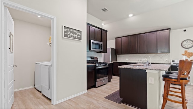 kitchen featuring visible vents, decorative backsplash, washer and clothes dryer, a sink, and appliances with stainless steel finishes