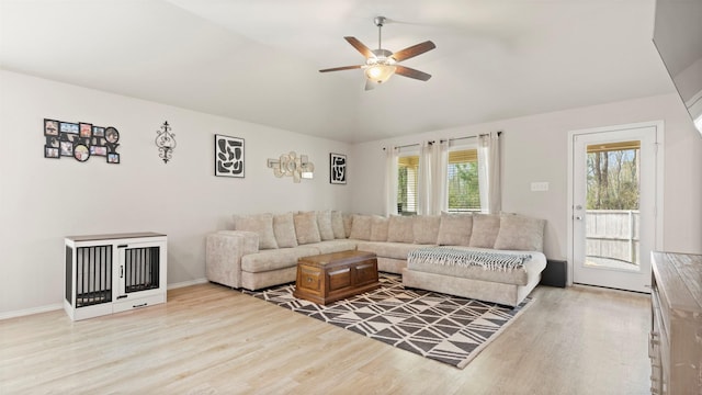 living room with baseboards, a ceiling fan, light wood-style flooring, and lofted ceiling