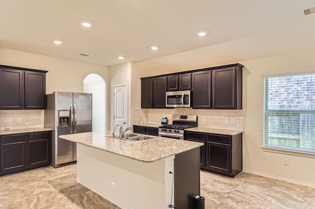 kitchen featuring plenty of natural light, arched walkways, decorative backsplash, and appliances with stainless steel finishes
