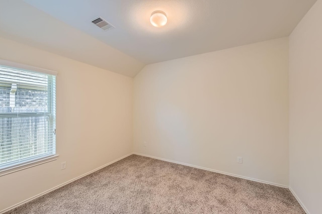 empty room featuring baseboards, visible vents, lofted ceiling, and carpet