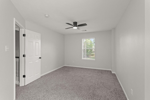carpeted spare room featuring ceiling fan, visible vents, and baseboards