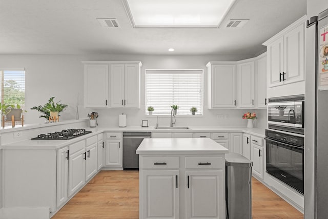kitchen featuring a sink, a peninsula, white cabinets, and stainless steel appliances