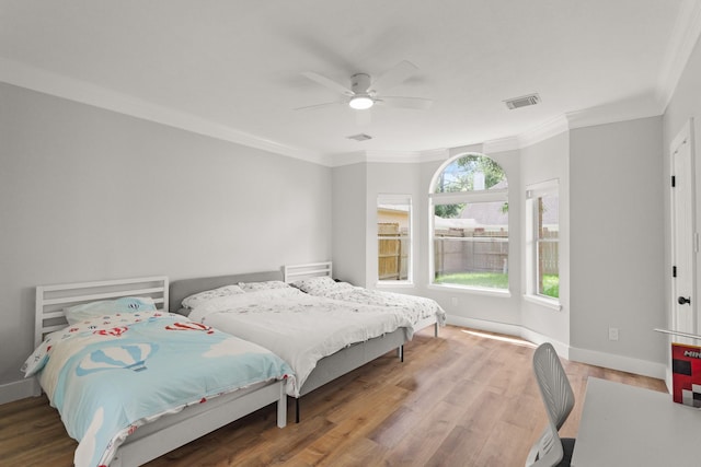 bedroom with visible vents, ornamental molding, a ceiling fan, and wood finished floors