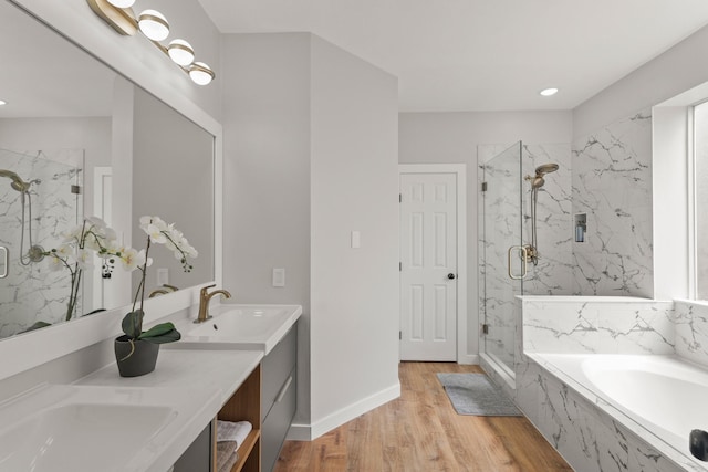 full bath featuring a garden tub, a sink, a marble finish shower, and wood finished floors