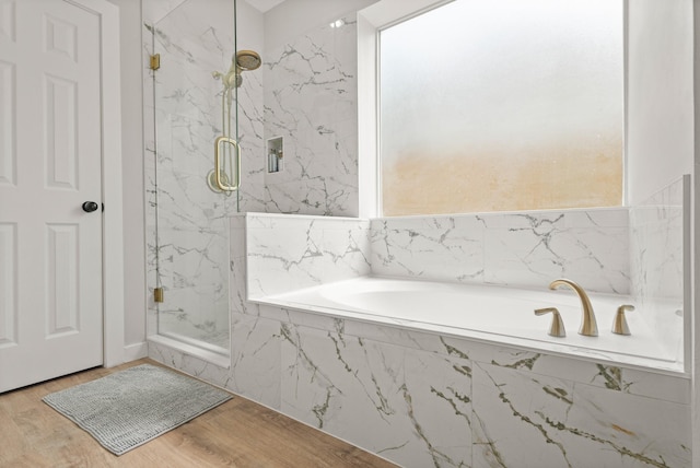 full bathroom with a marble finish shower, a bath, and wood finished floors