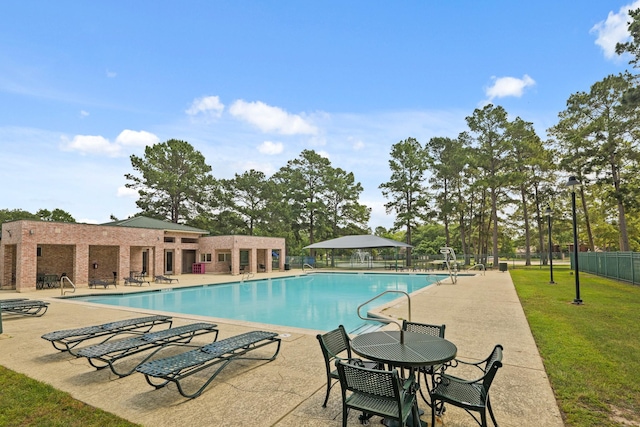 community pool with a patio, fence, and a yard