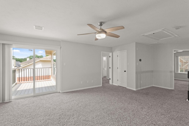 carpeted empty room featuring baseboards, ceiling fan, attic access, and visible vents