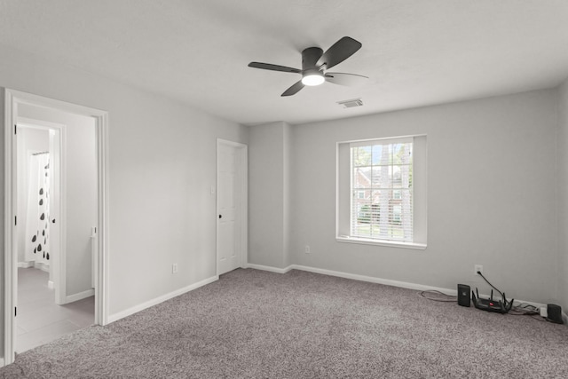 carpeted spare room featuring visible vents, baseboards, and ceiling fan
