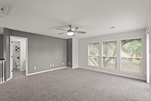 unfurnished bedroom featuring visible vents, baseboards, attic access, carpet flooring, and ensuite bath