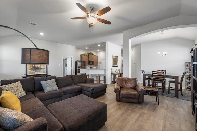 11310 Cora Ln, Willis, TX 77318 - living room with visible vents, arched walkways, vaulted ceiling, light wood-type flooring, and ceiling fan with notable chandelier