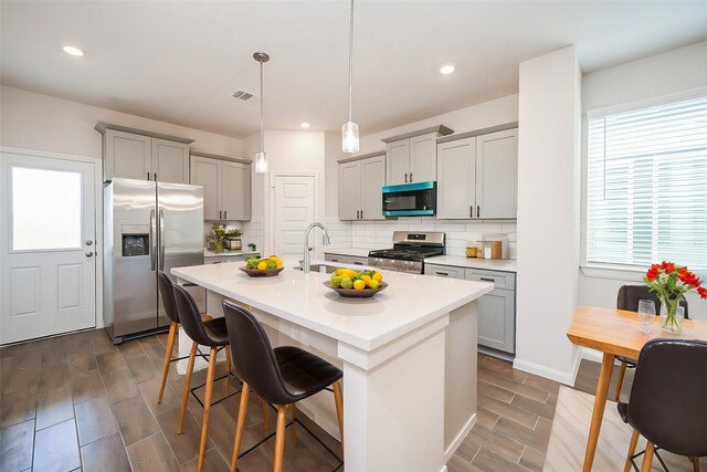 14515 Aston Pine Dr, Houston, TX 77032 - kitchen featuring wood finish floors, appliances with stainless steel finishes, a breakfast bar, light countertops, and gray cabinetry