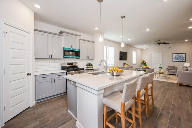 14515 Aston Pine Dr, Houston, TX 77032 - kitchen featuring open floor plan, wood tiled floor, a sink, gray cabinetry, and stainless steel appliances