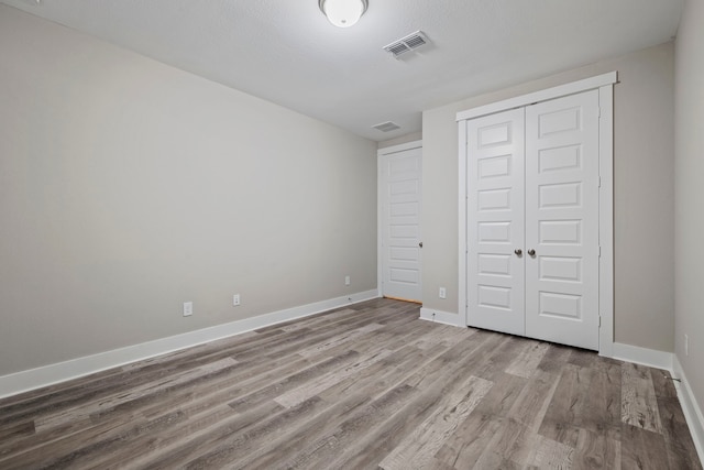 1220 Sloane Manor Trce, Houston, TX 77043 - unfurnished bedroom with baseboards, a closet, wood finished floors, and visible vents