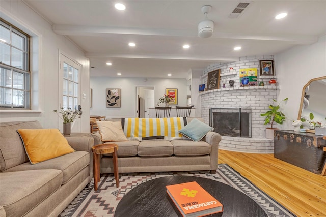 living area with a fireplace, recessed lighting, beam ceiling, and wood finished floors