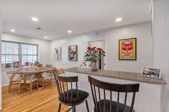 kitchen with recessed lighting, a kitchen bar, light wood-style flooring, and visible vents