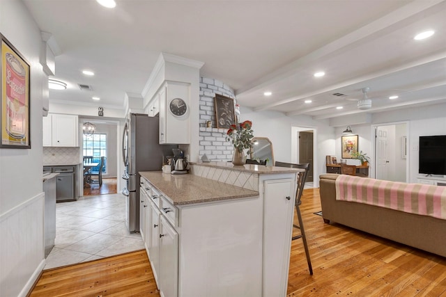 kitchen featuring decorative backsplash, a breakfast bar area, white cabinets, open floor plan, and recessed lighting